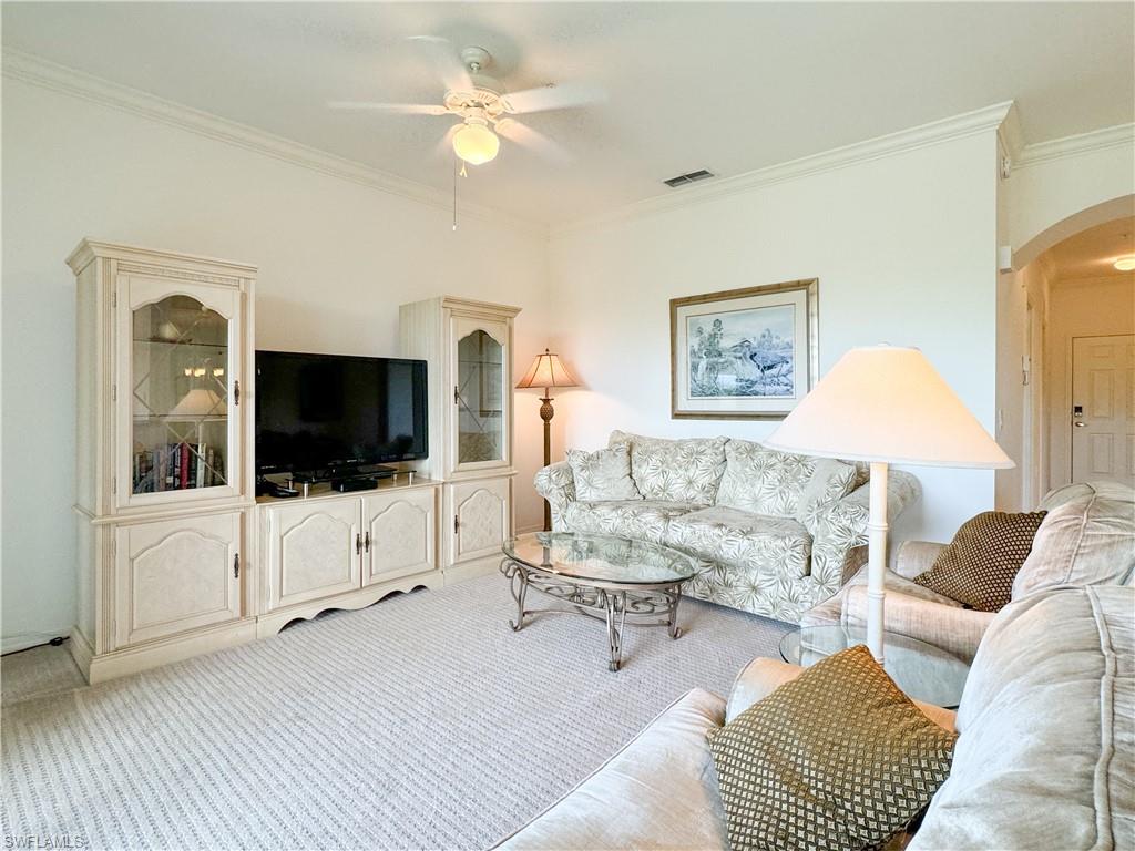 Living room featuring crown molding, light colored carpet, and ceiling fan