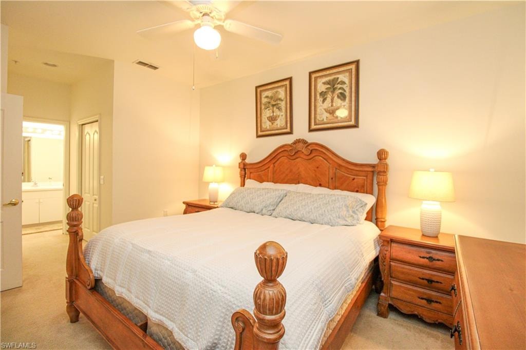 Carpeted bedroom with connected bathroom and ceiling fan