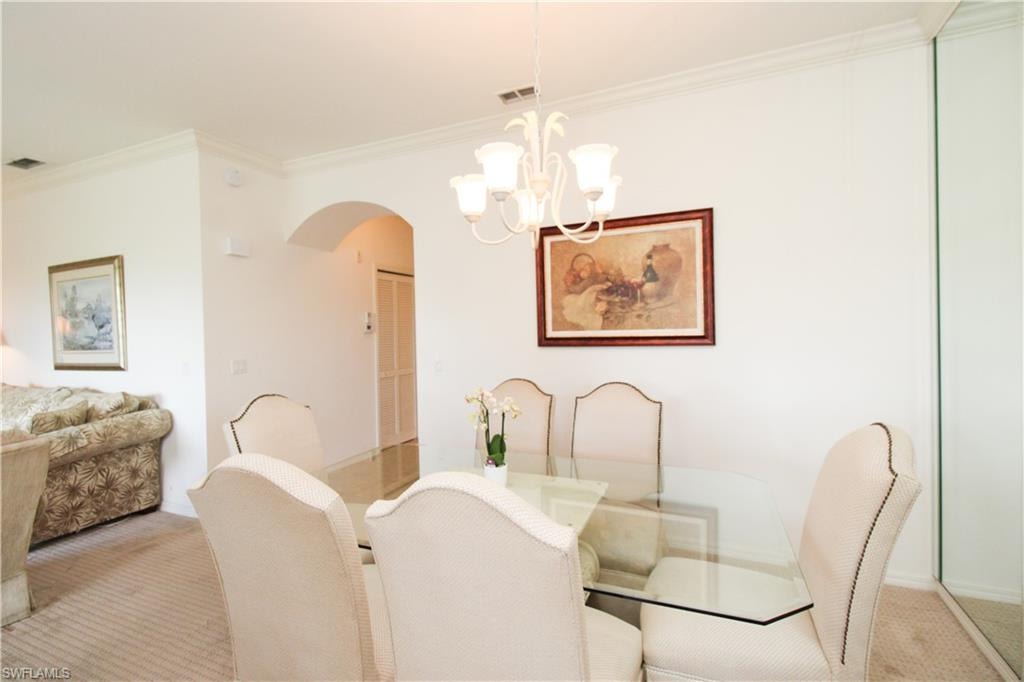 Dining space with crown molding, a notable chandelier, and light colored carpet
