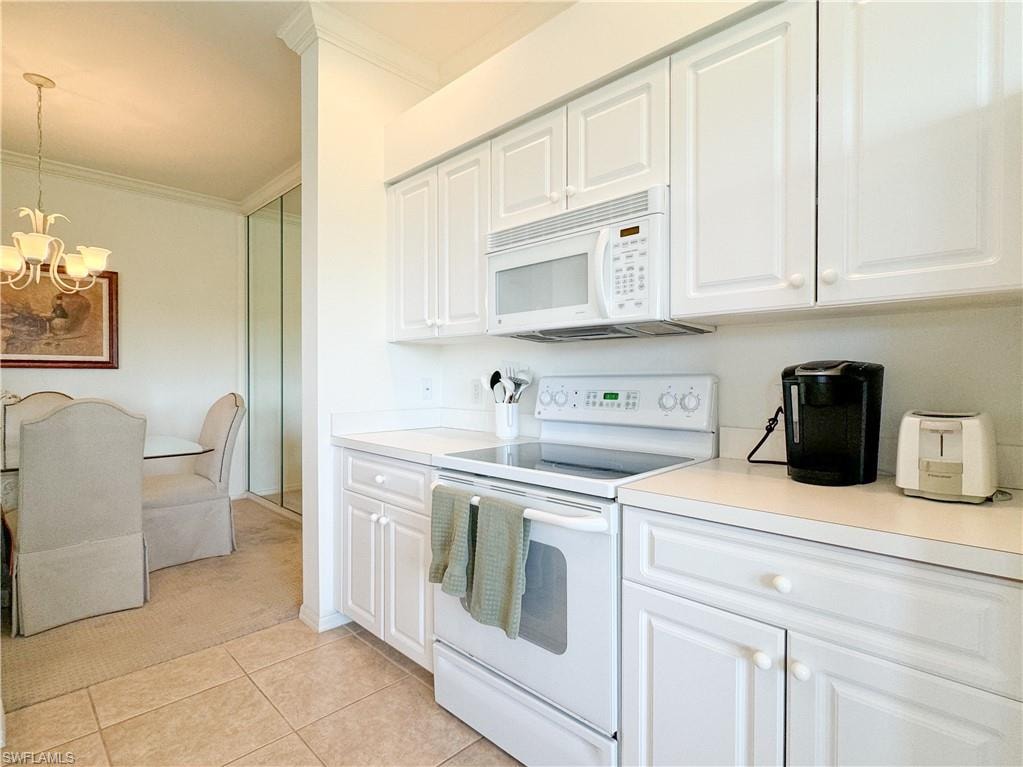 Kitchen with crown molding, white cabinets, white appliances, and a notable chandelier