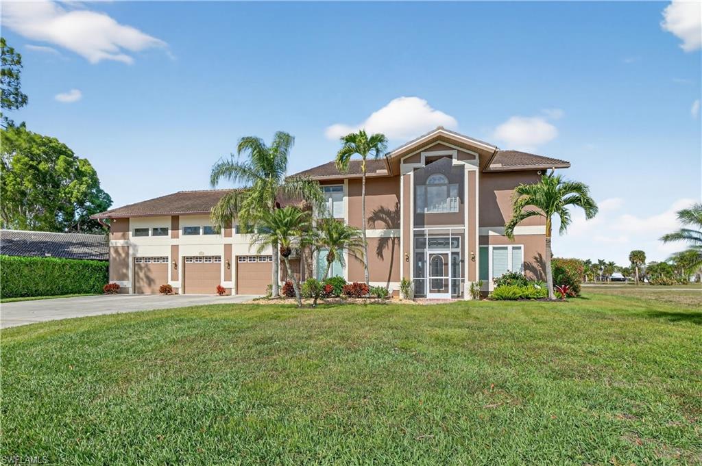 View of front facade featuring a front lawn, stucco siding, driveway, and a garage