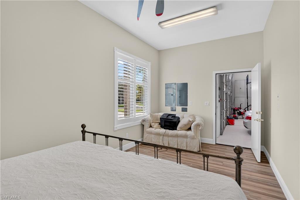 Hangar bedroom or office Bedroom featuring wood finished floors, electric panel, and a ceiling fan