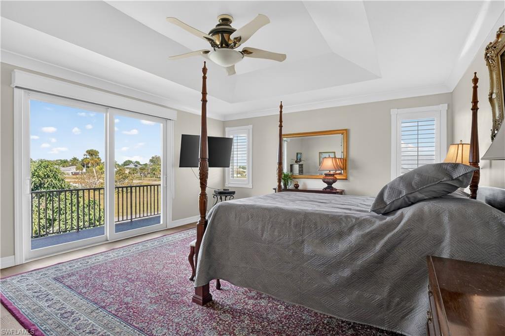Bedroom with access to exterior, a raised ceiling, and ceiling fan