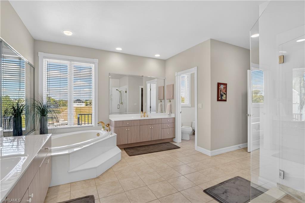 Bathroom with a shower stall, two vanities, a bath, light tile patterned flooring, and a bidet