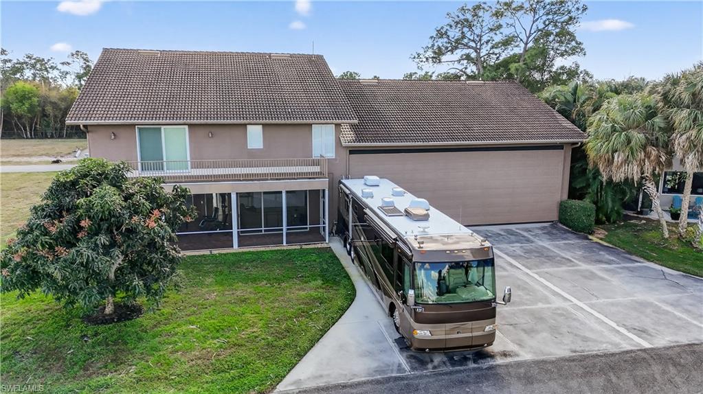 View of front of house featuring a tile roof, a front lawn, a sunroom, and stucco siding
