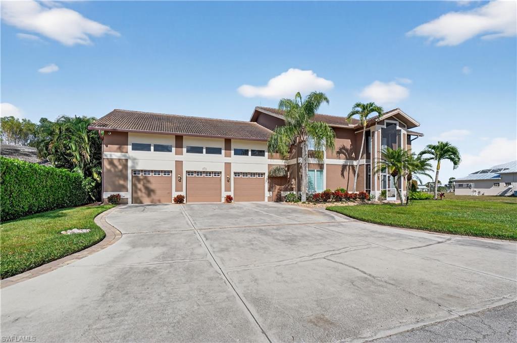 View of front facade featuring a front yard, driveway, a tiled roof, stucco siding, and a garage
