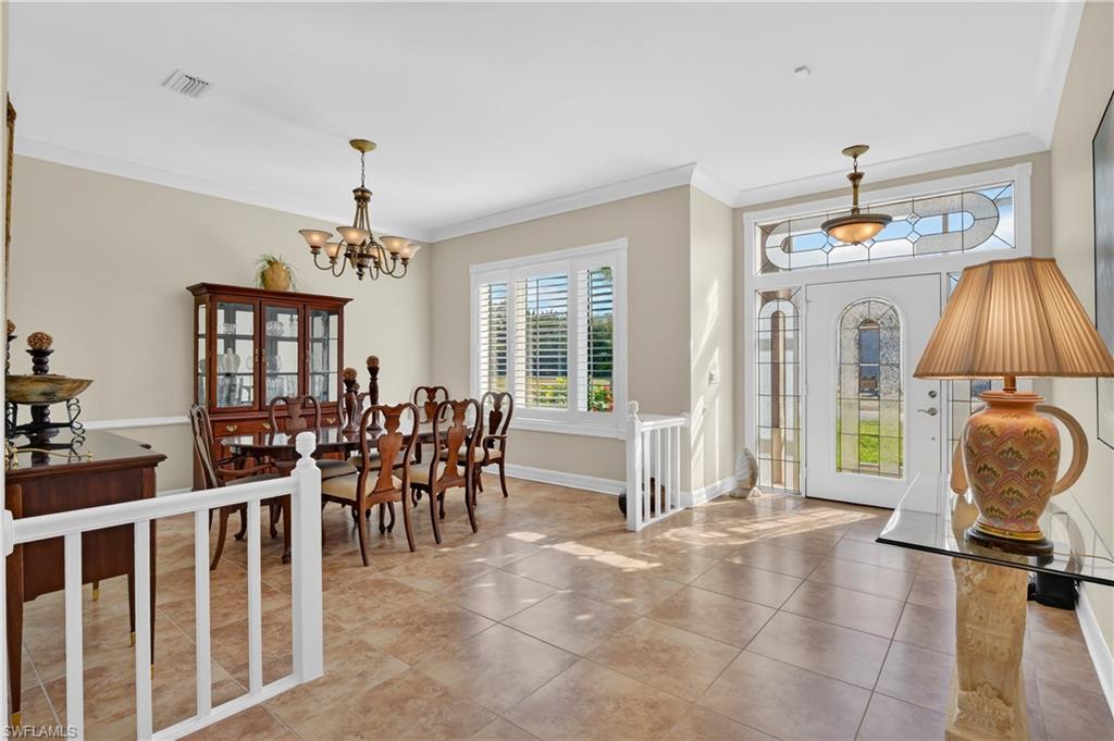 Entrance foyer with ornamental molding, tile patterned floors, and a chandelier