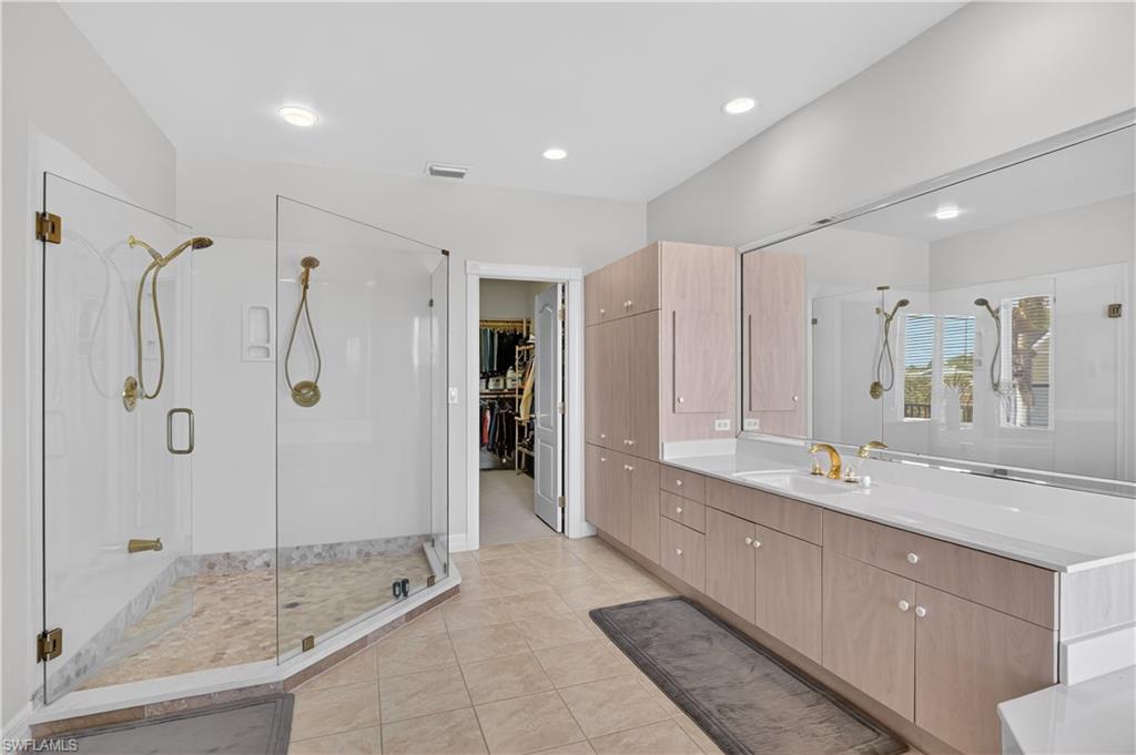 Bathroom featuring a stall shower, a walk in closet, vanity, light tile patterned floors, and recessed lighting