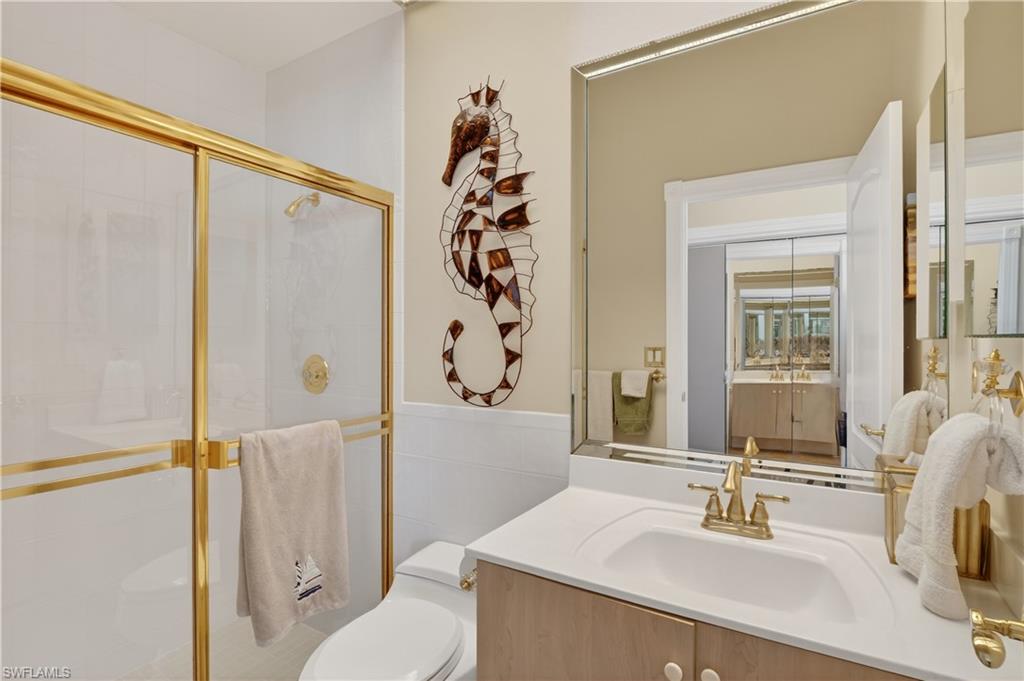 Bathroom with a shower stall, vanity, and tile walls