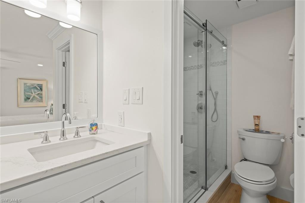 Bathroom featuring a white vanity with an integrated sink, polished chrome faucet, framed mirror, and a glass-enclosed shower with tile surround and a rain showerhead