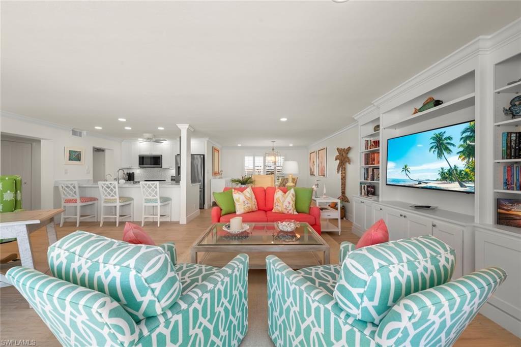 Open-concept living area featuring light wood-finish flooring, recessed lighting, and a white built-in media center with shelving