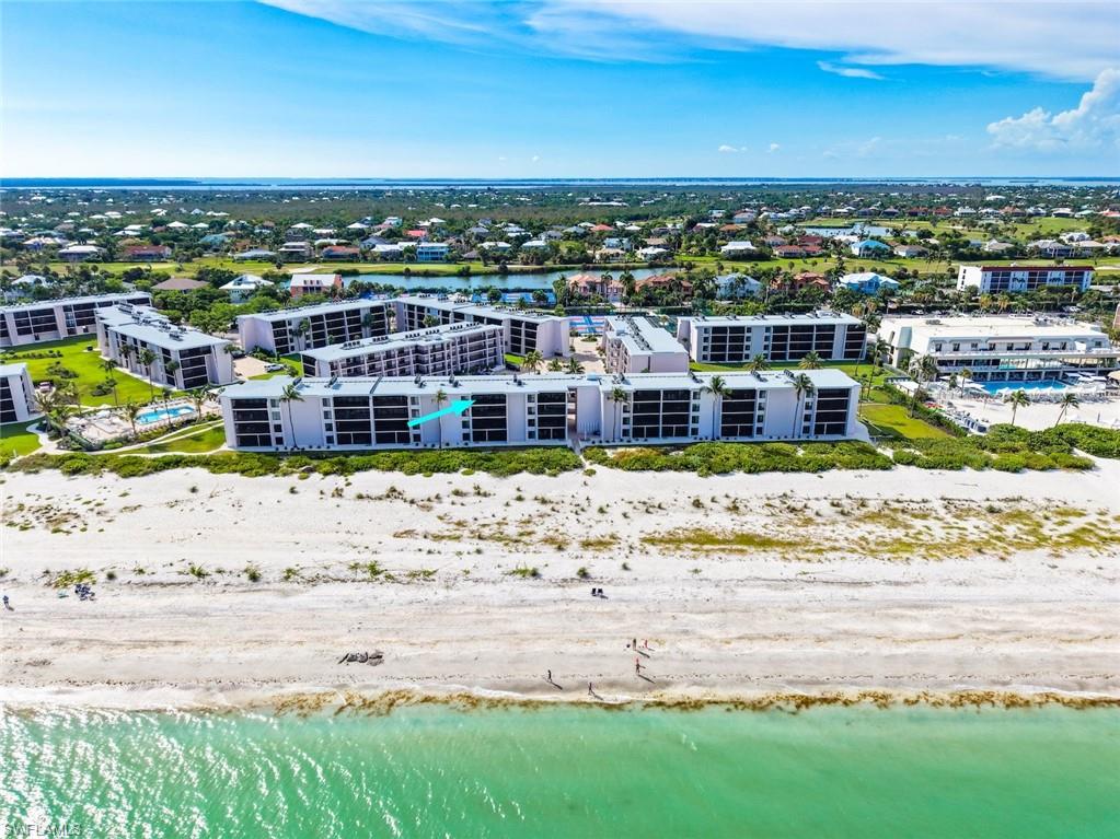 Beachfront condominium building with direct beach access, multiple balconies, and integrated landscaping