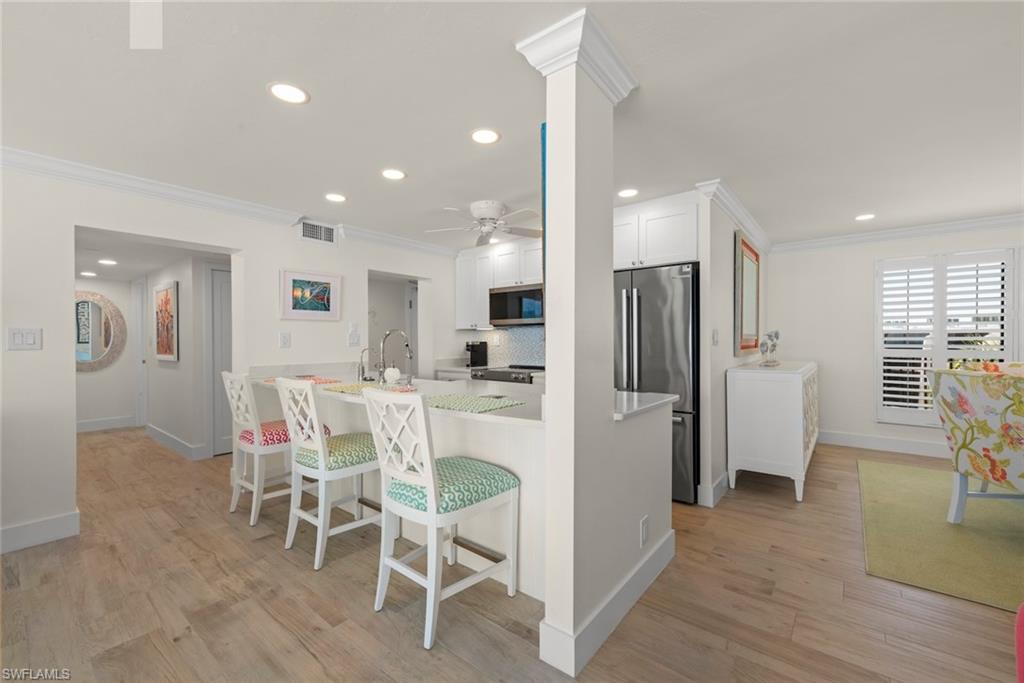 Kitchen featuring a breakfast bar with seating, white cabinetry, stainless steel refrigerator, and recessed lighting