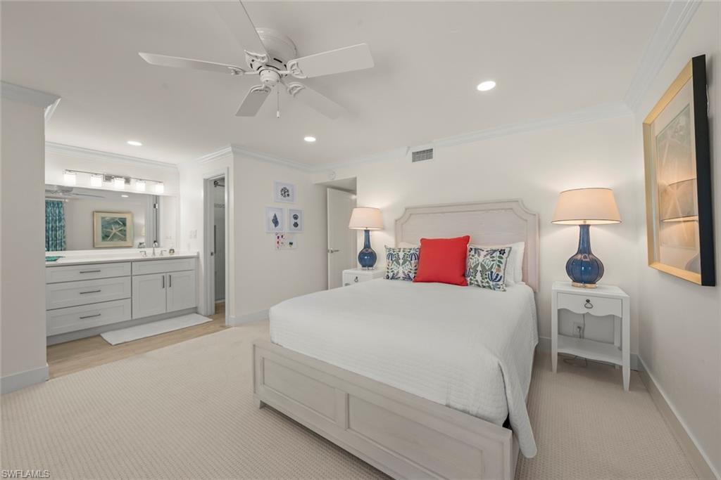 Spacious bedroom with light-toned carpeting and an integrated ensuite featuring a double vanity with light cabinetry