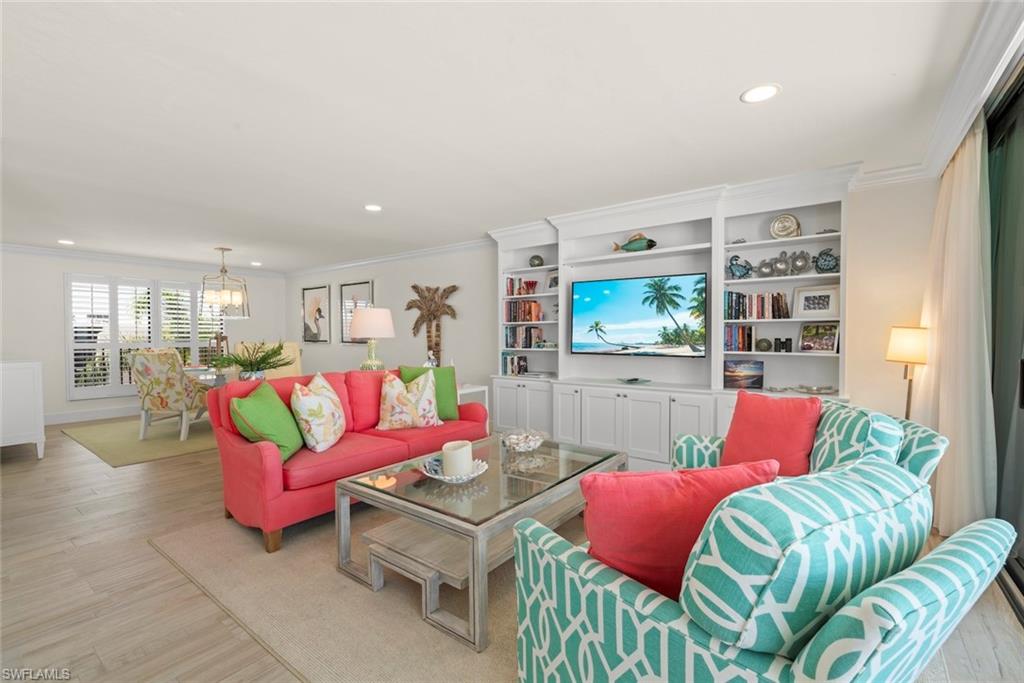 Open-concept living space with light-tone wood-finish flooring, recessed lighting, and crown molding