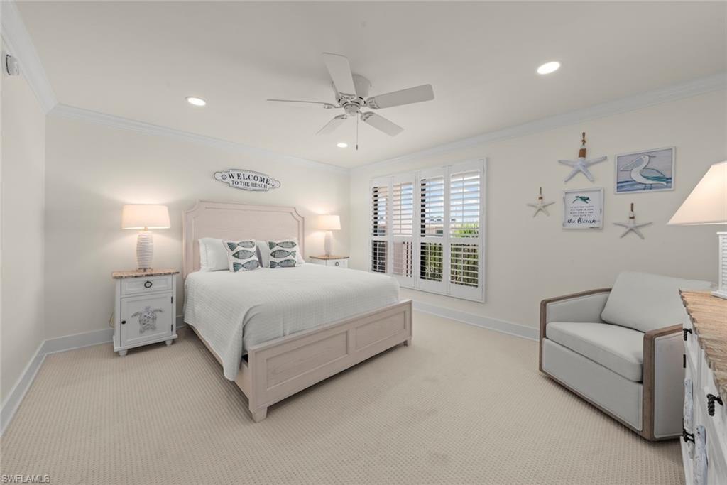 Spacious room featuring neutral carpeting, white plantation shutters, crown molding, and recessed lighting