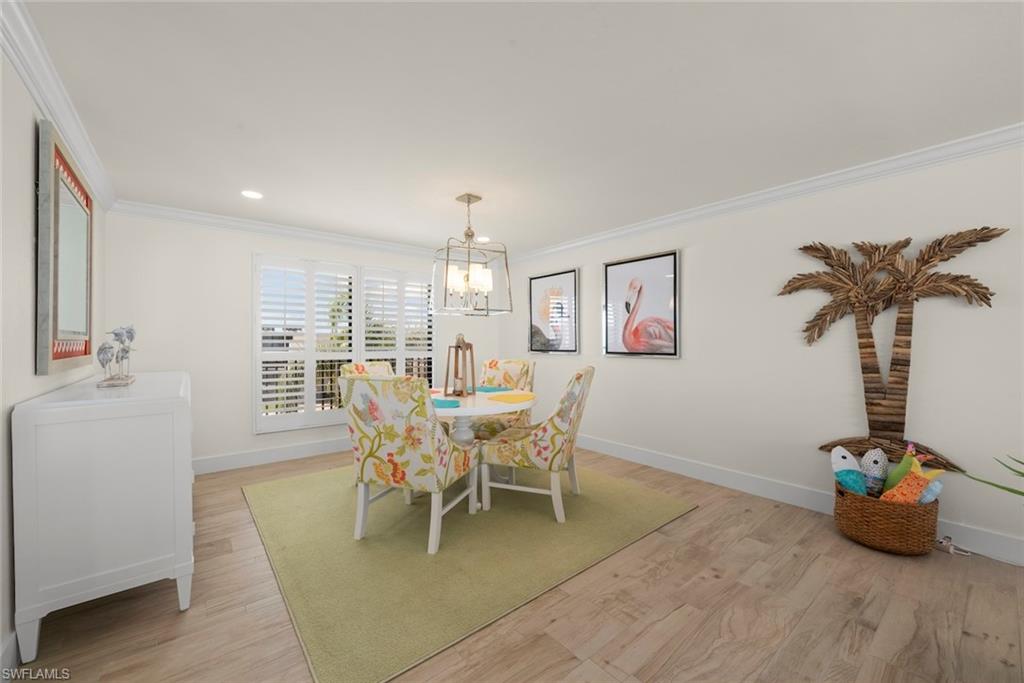 Light-filled room featuring wood-finish flooring, white crown molding, and plantation shutters