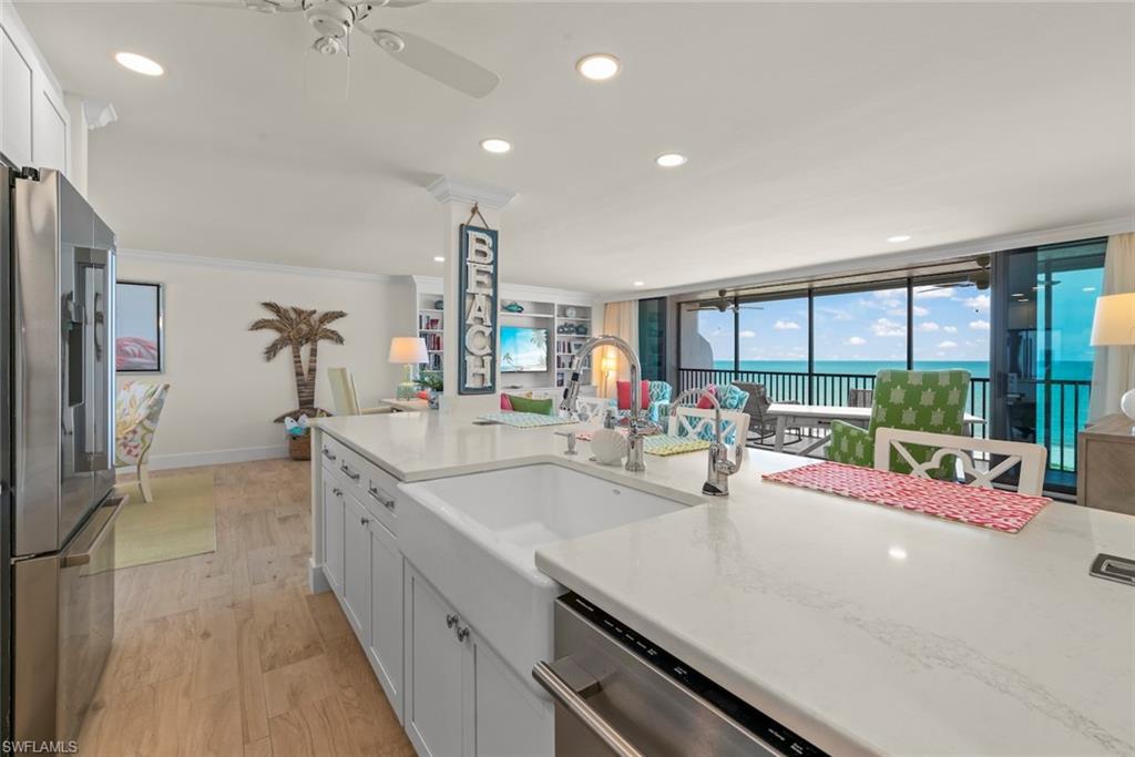 Kitchen featuring an oversized island with a farmhouse sink, stainless steel appliances, recessed lighting, and wood-finish flooring