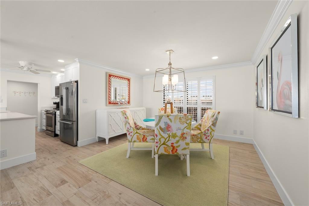 Dining area featuring wood-finish flooring, a contemporary chandelier, and a window with white louvered shutters
