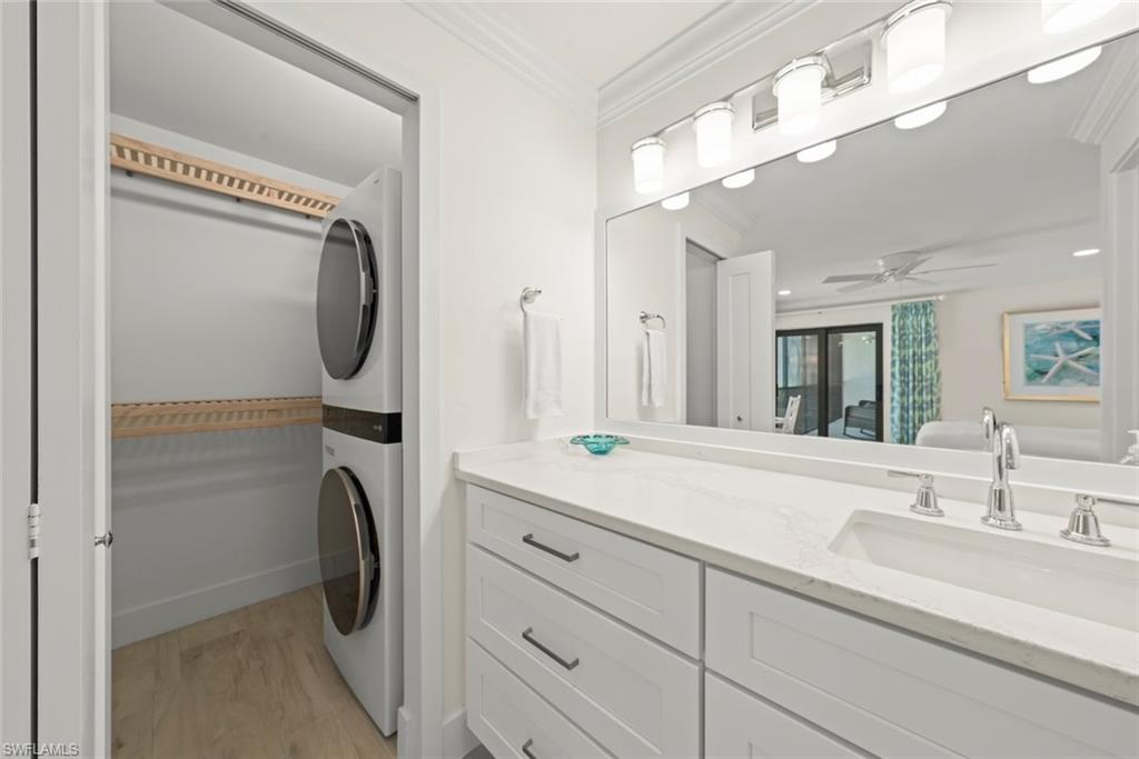 Bathroom vanity featuring white shaker cabinetry, an integrated rectangular sink, and a light-toned countertop. Full size w/d in closet