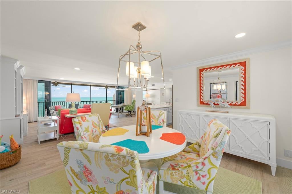 Spacious open-concept living area featuring wood-finish flooring, a contemporary chandelier, and a built-in sideboard with geometric detailing