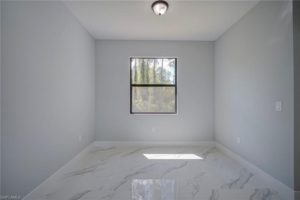 Spare room with light marble finish flooring and baseboards