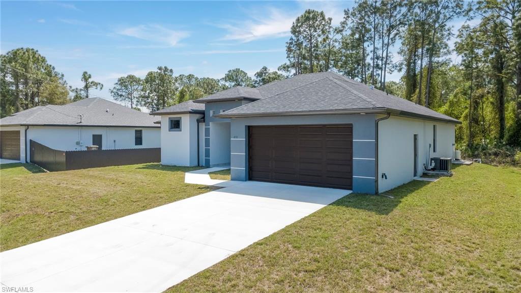 View of front of property with a front yard, an attached garage, and stucco siding