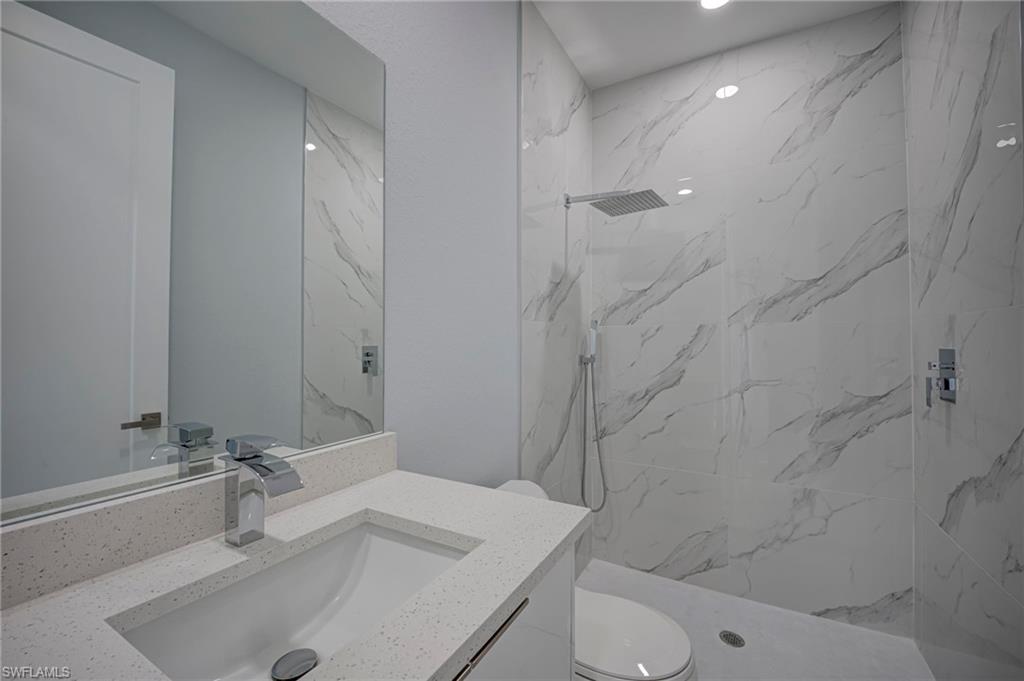 Bathroom featuring vanity and a marble finish shower
