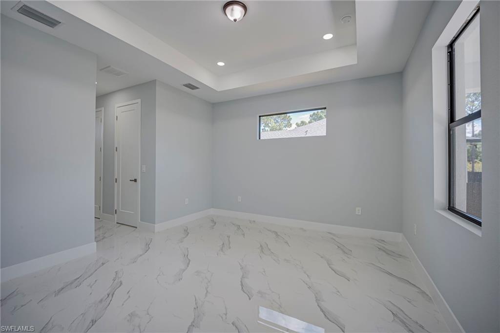 Spare room featuring recessed lighting, a tray ceiling, and light marble finish floors