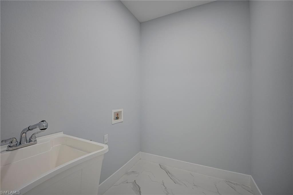 Laundry room featuring washer hookup and light marble finish floors