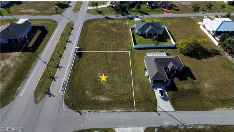 Expansive corner lot featuring a grassy expanse, street access on two sides, and proximity to surrounding residential properties