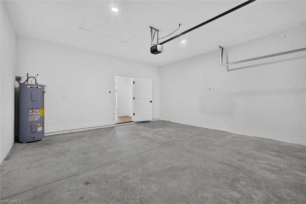 Spacious garage featuring a concrete floor, bright white walls, recessed lighting, and a water heater