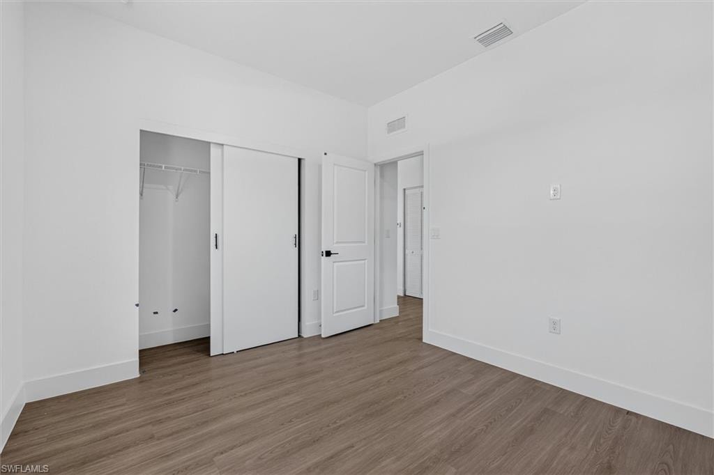 Room featuring wood-finish flooring, white walls, and white baseboards