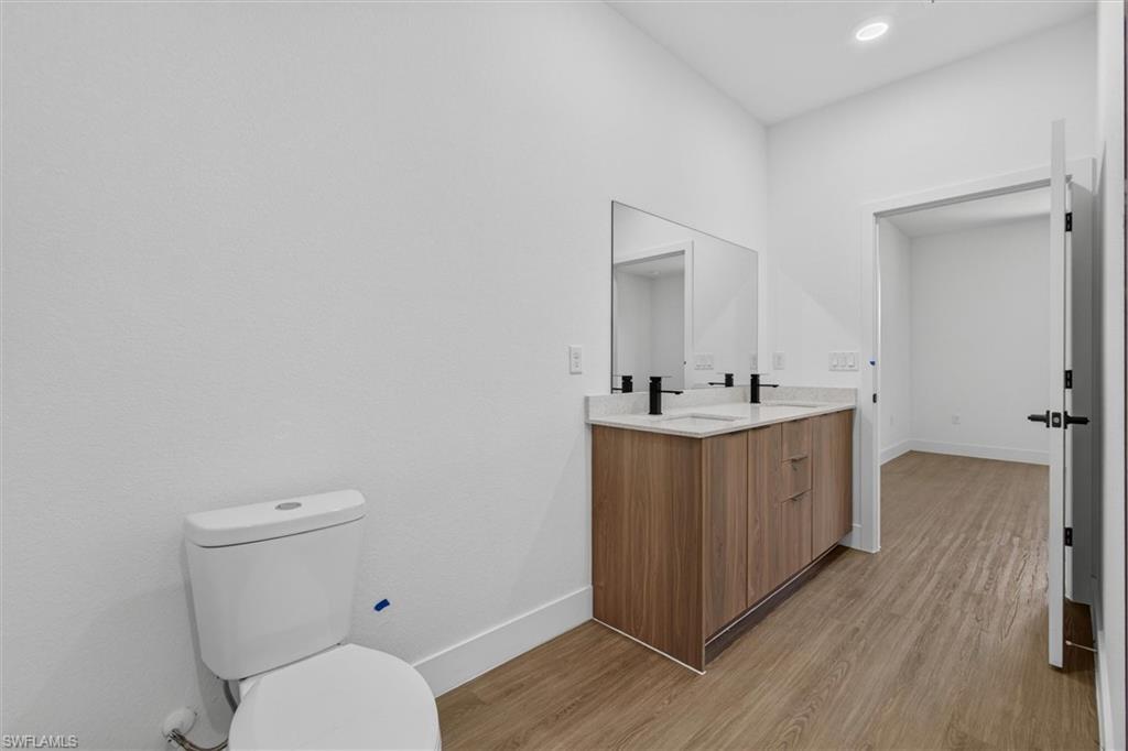 Bathroom featuring a dual vanity with a light-toned countertop, wood-finish cabinetry, and matte black fixtures