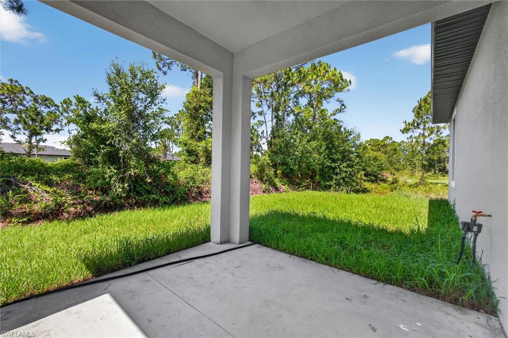 Covered concrete patio with columns and a verdant lawn