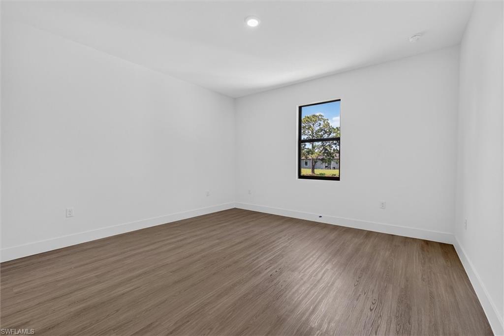 Spacious room featuring light wood-finish flooring, crisp white walls, and a recessed ceiling light