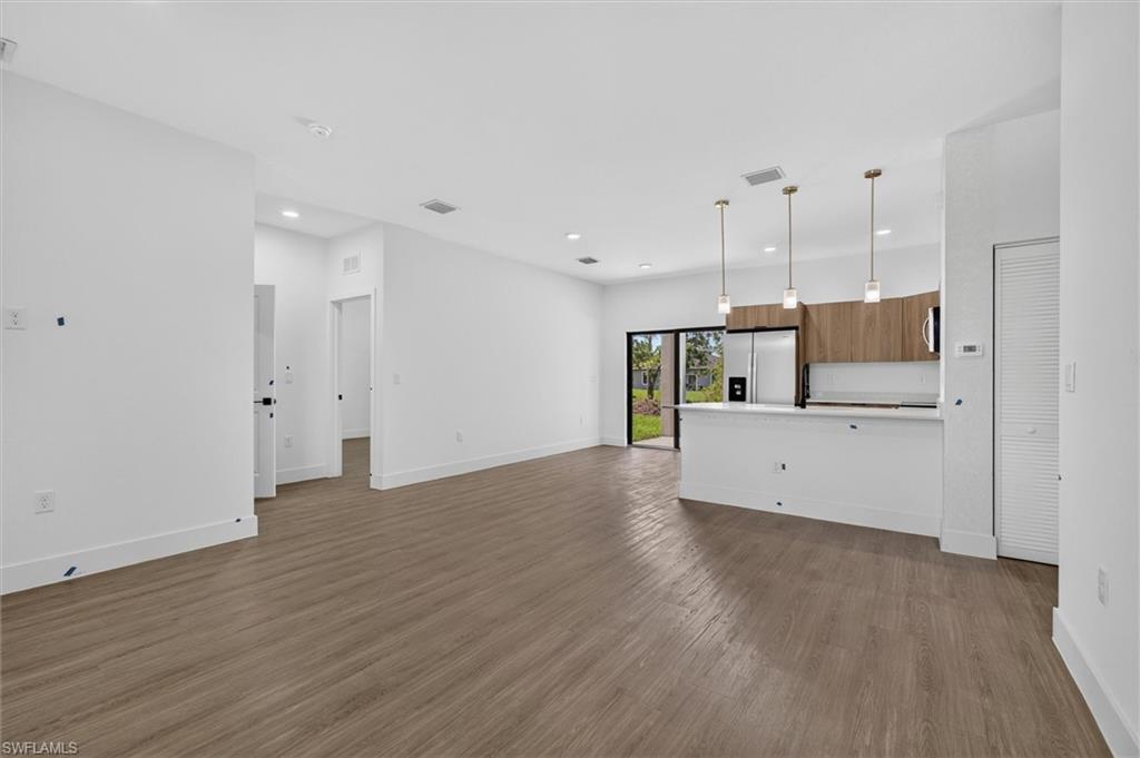 Open-concept living space featuring wood-finish flooring, recessed lighting, and a kitchen island with pendant lighting