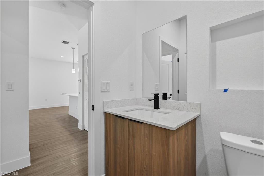 Modern vanity with wood-finish cabinetry, white countertop, and integrated sink