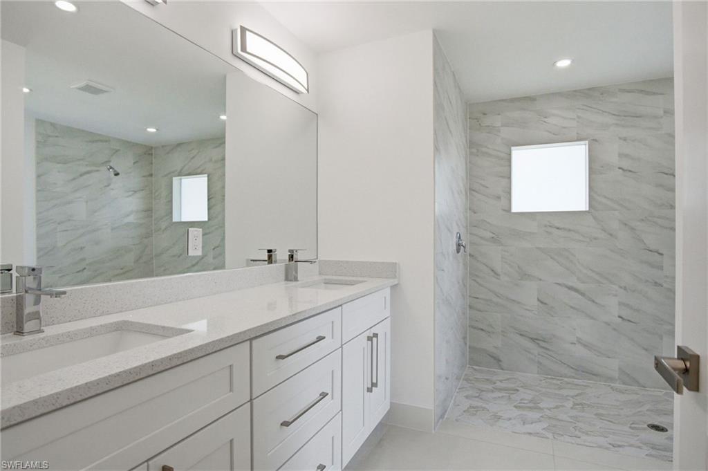 Contemporary bathroom featuring a dual vanity with white shaker cabinetry, light speckled countertops, and brushed nickel hardware