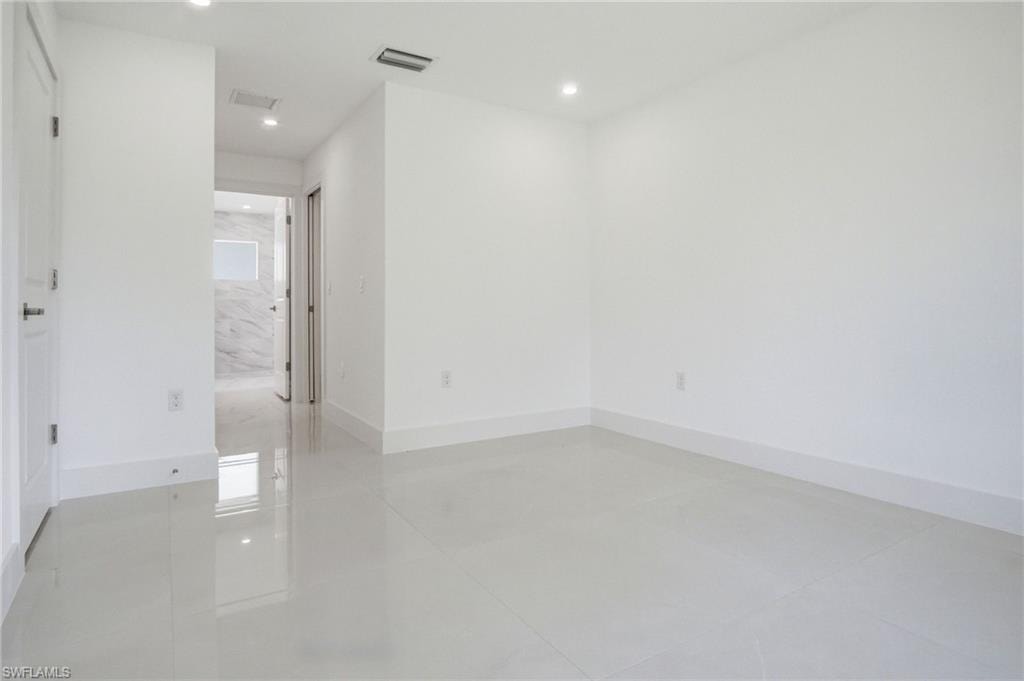 Spacious room featuring light-toned tile flooring, recessed lighting, and a neutral white wall palette