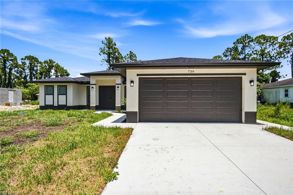 Contemporary home exterior featuring a two-car garage, concrete driveway, and a covered entry