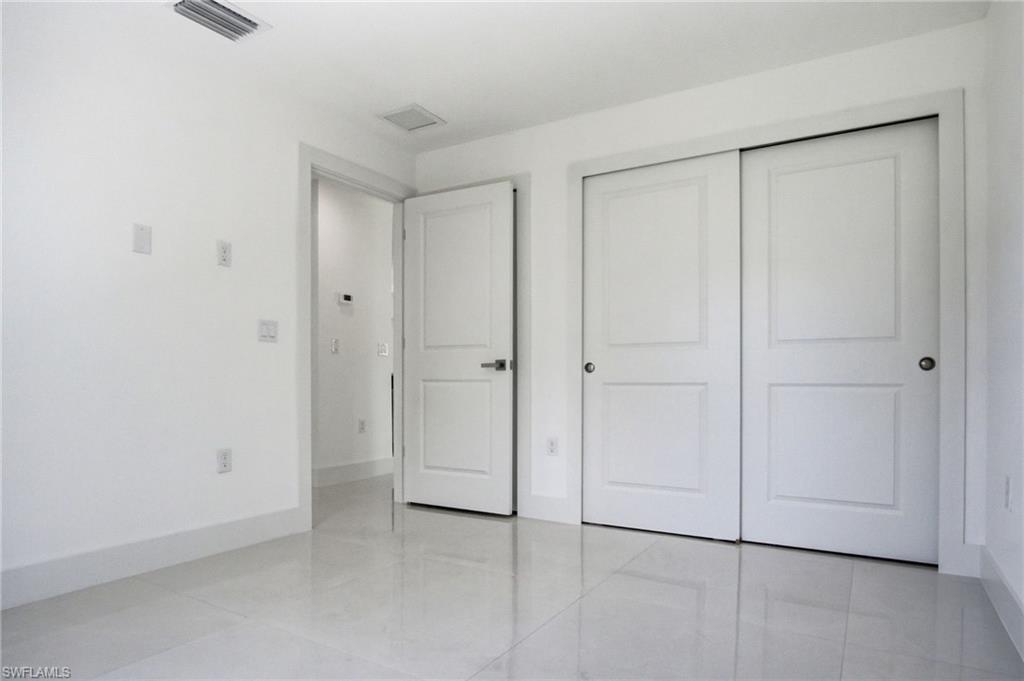 Room featuring bright white walls, contemporary white baseboards, and glossy light-colored tile flooring