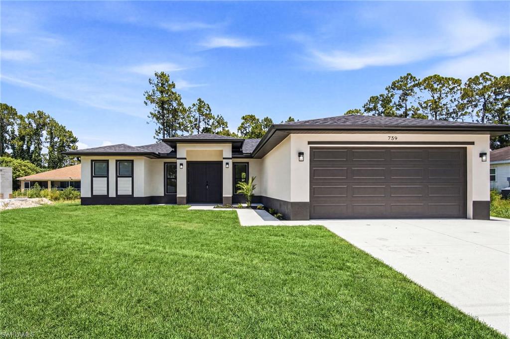 Contemporary single-story exterior featuring a two-car garage, dark entry doors, and a light stucco facade with dark accents