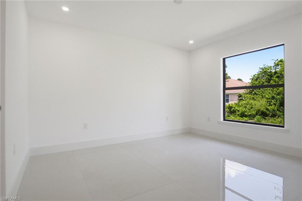 Spacious room featuring neutral paint, large format tile flooring, recessed lighting, and a prominent window with dark framing