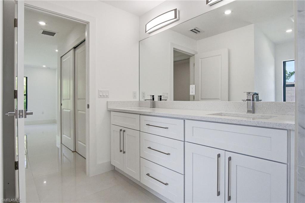 Double vanity with integrated sinks, speckled countertops, and chrome fixtures