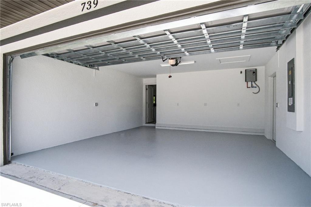 Spacious garage featuring a durable light gray epoxy floor coating, white painted walls, and an overhead garage door opener