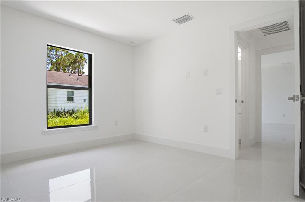 Bright interior room featuring white walls, white baseboards, and a single window with black trim