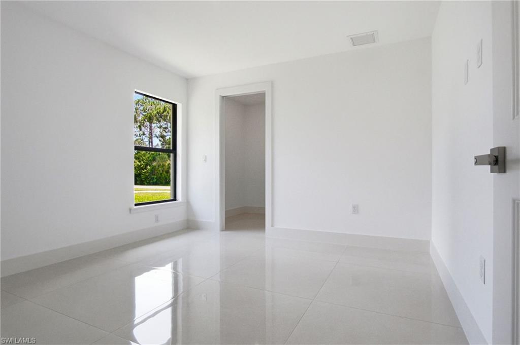 Bright interior space featuring large format light-toned tile flooring, clean white walls, and a window with black trim