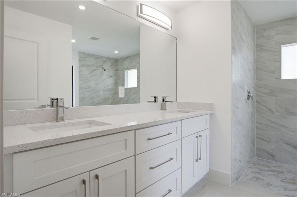 Dual vanity with white cabinetry and integrated sinks, complemented by chrome fixtures and an expansive mirror