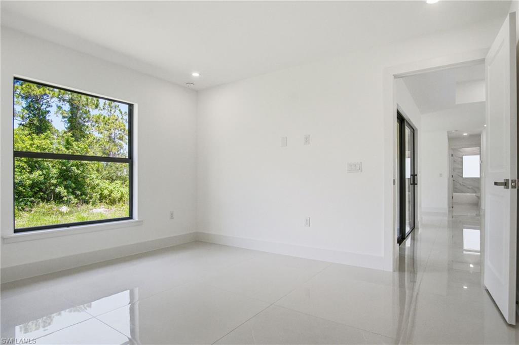 Bright interior space with a large window, white walls, recessed lighting, and glossy tile flooring